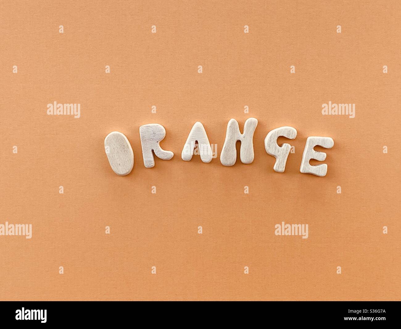 Parola arancione composta da lettere in legno fatte a mano di colore arancione Foto Stock