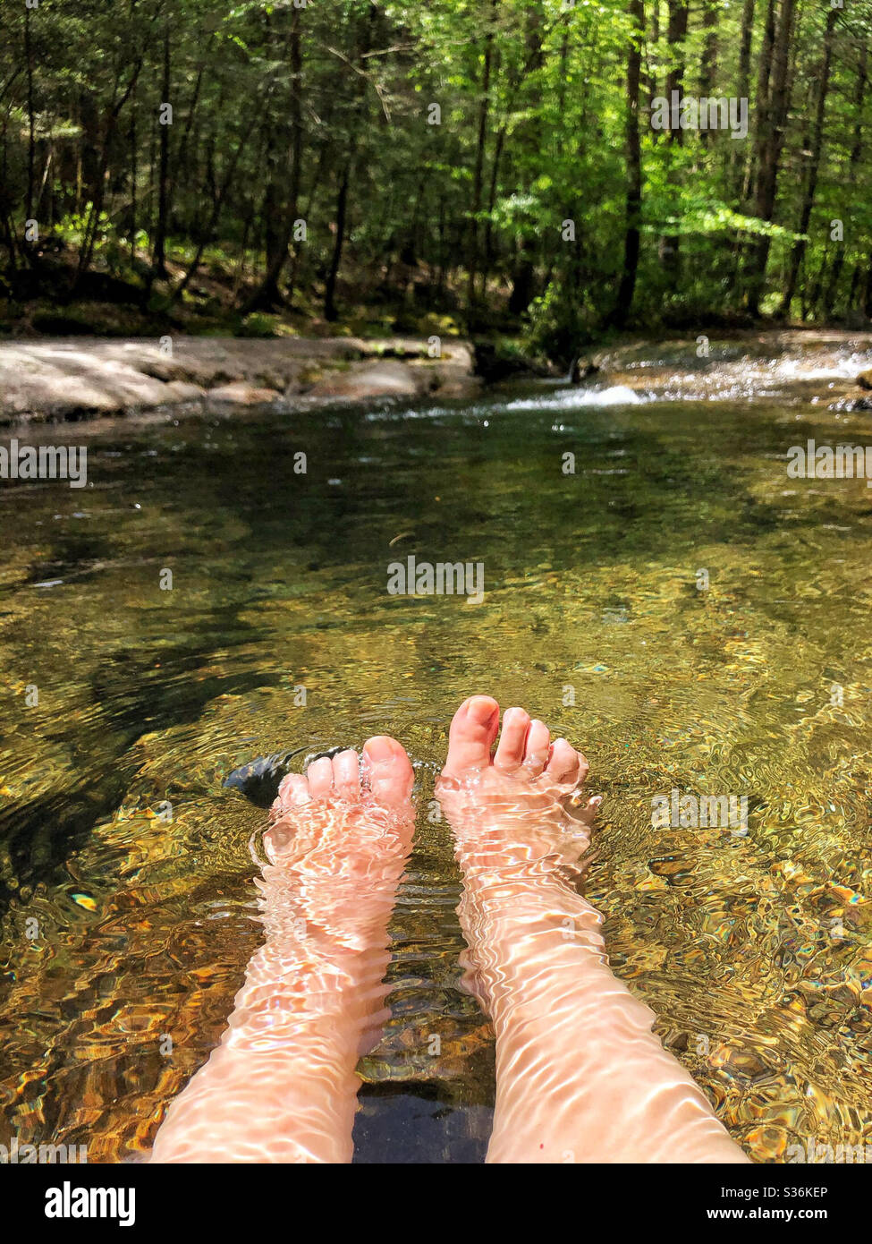 Donna che si rilassa in un fiume in montagna, in una piscina Foto Stock