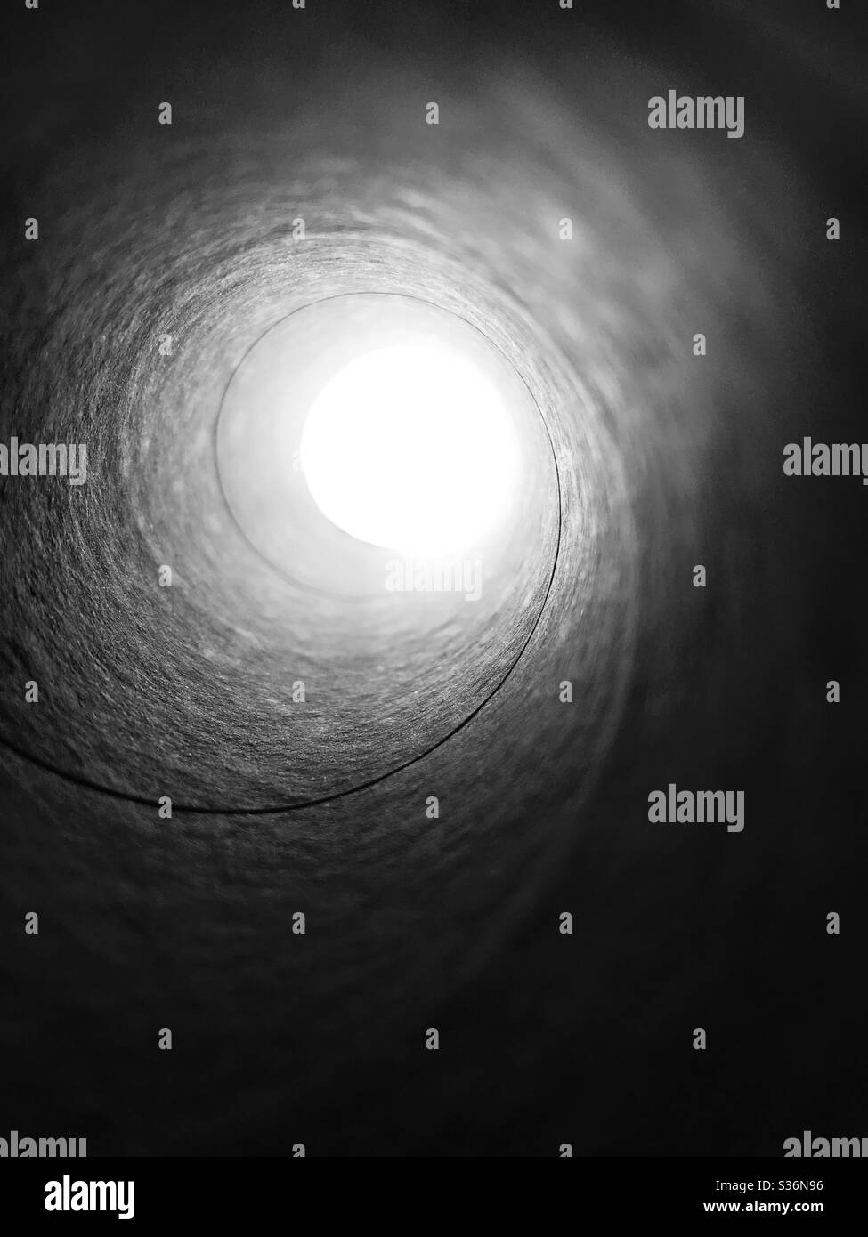 Vista spettacolare del cielo attraverso un rotolo di tessuto vuoto a spirale in modalità bianco e nero, immaginazione per raggio di speranza Foto Stock