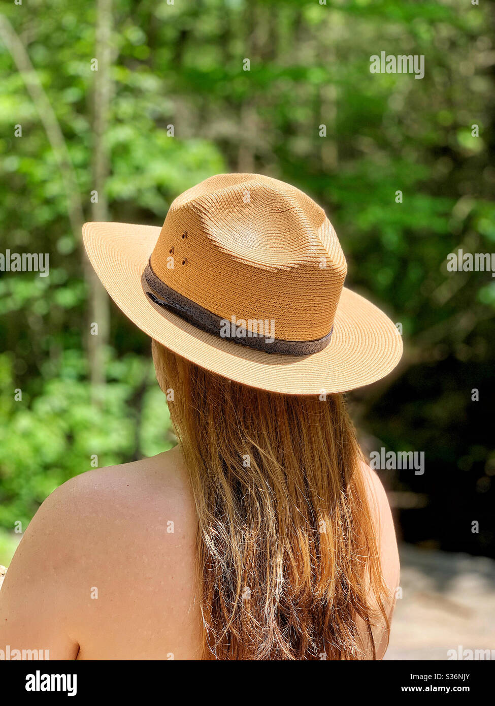 Donna in cappello ranger e abito senza dorso in cortile Foto Stock