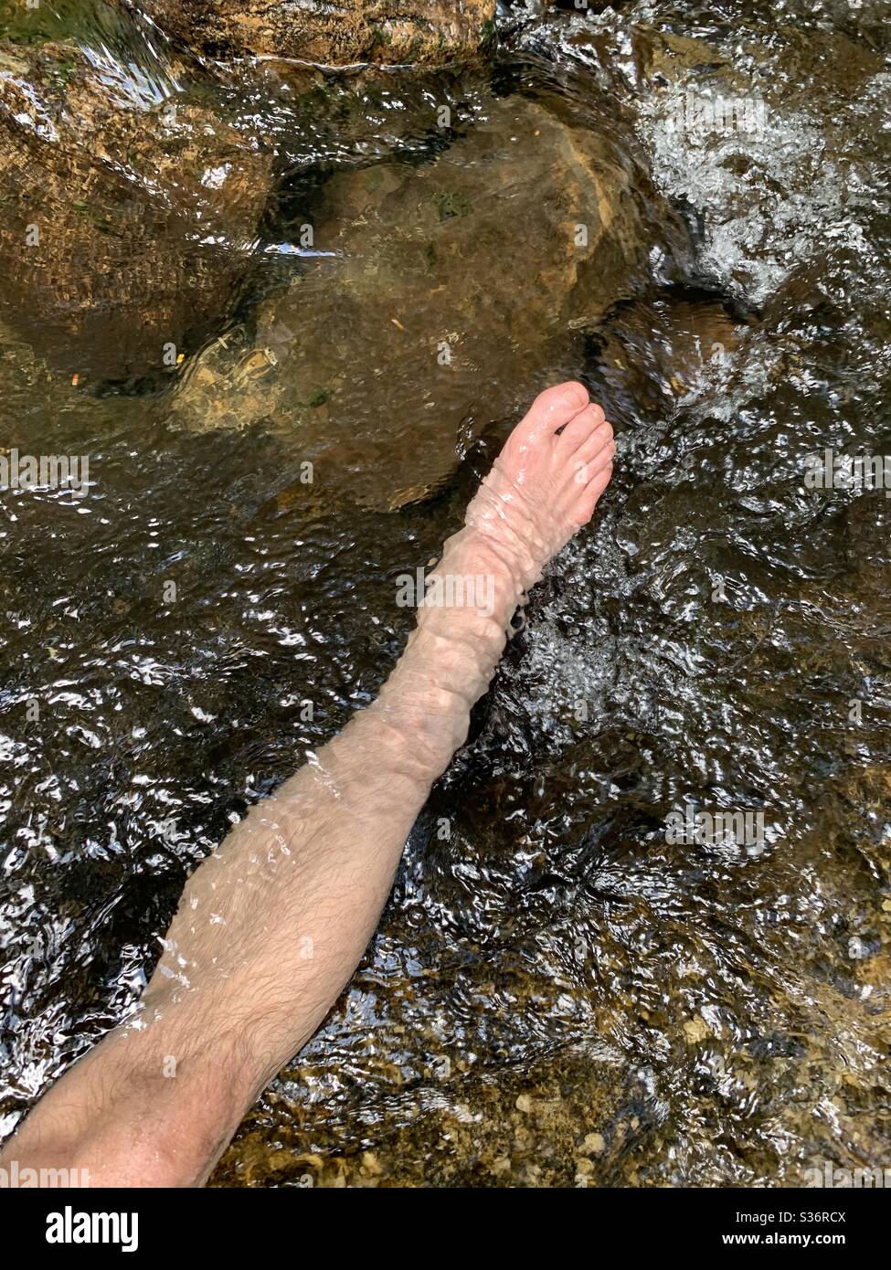 Gamba dell’uomo in un torrente di gelo in montagna nel parco Foto Stock