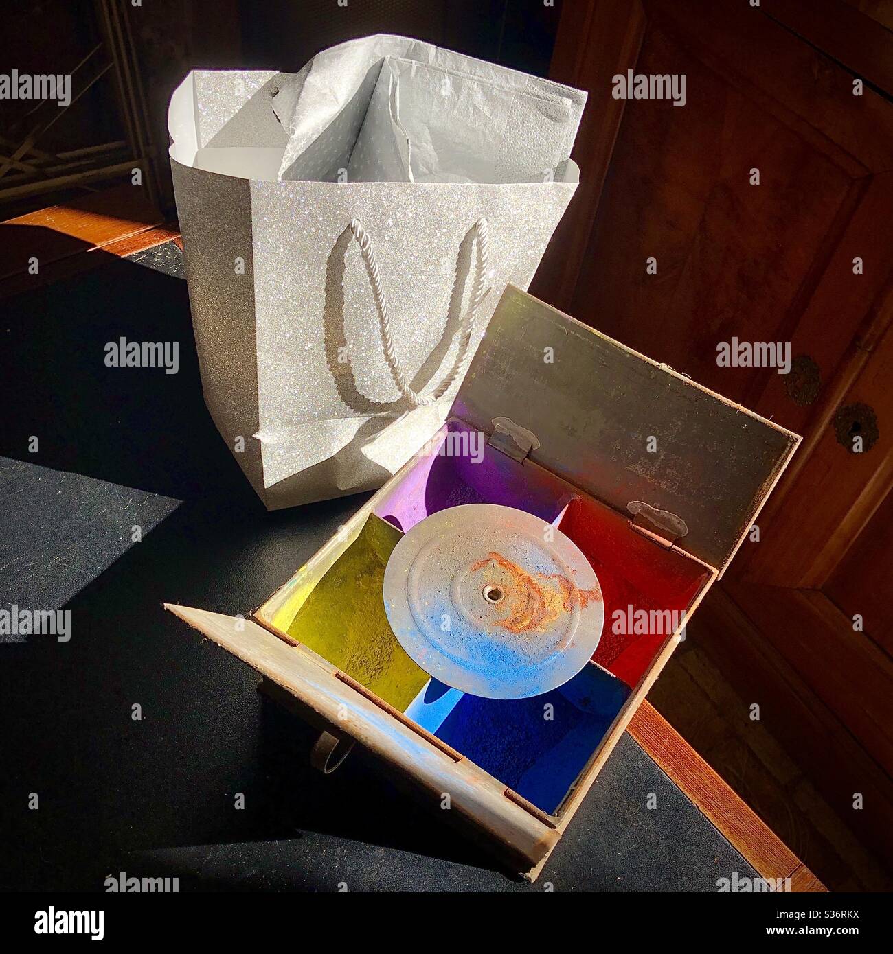 Vecchia scatola di metallo di tin di vernici a polvere colorate e nuovo sacchetto di trasporto di glitter argento still-life. Foto Stock