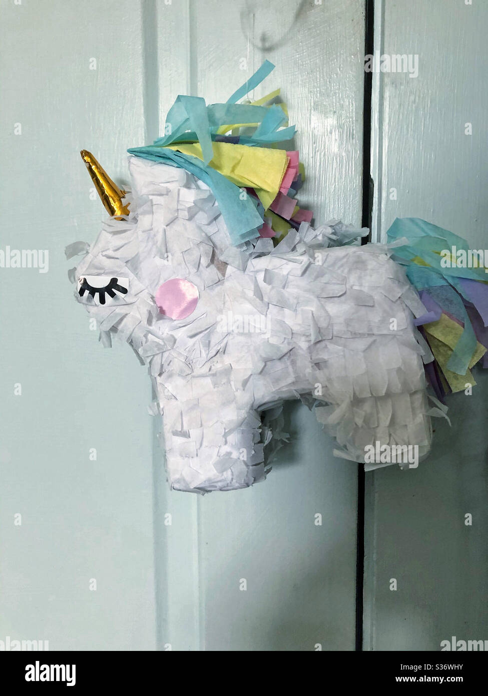 Il bambino unicorn piñata attende pacificamente per essere schierato in una festa - Immagine stock catturata con smartphone