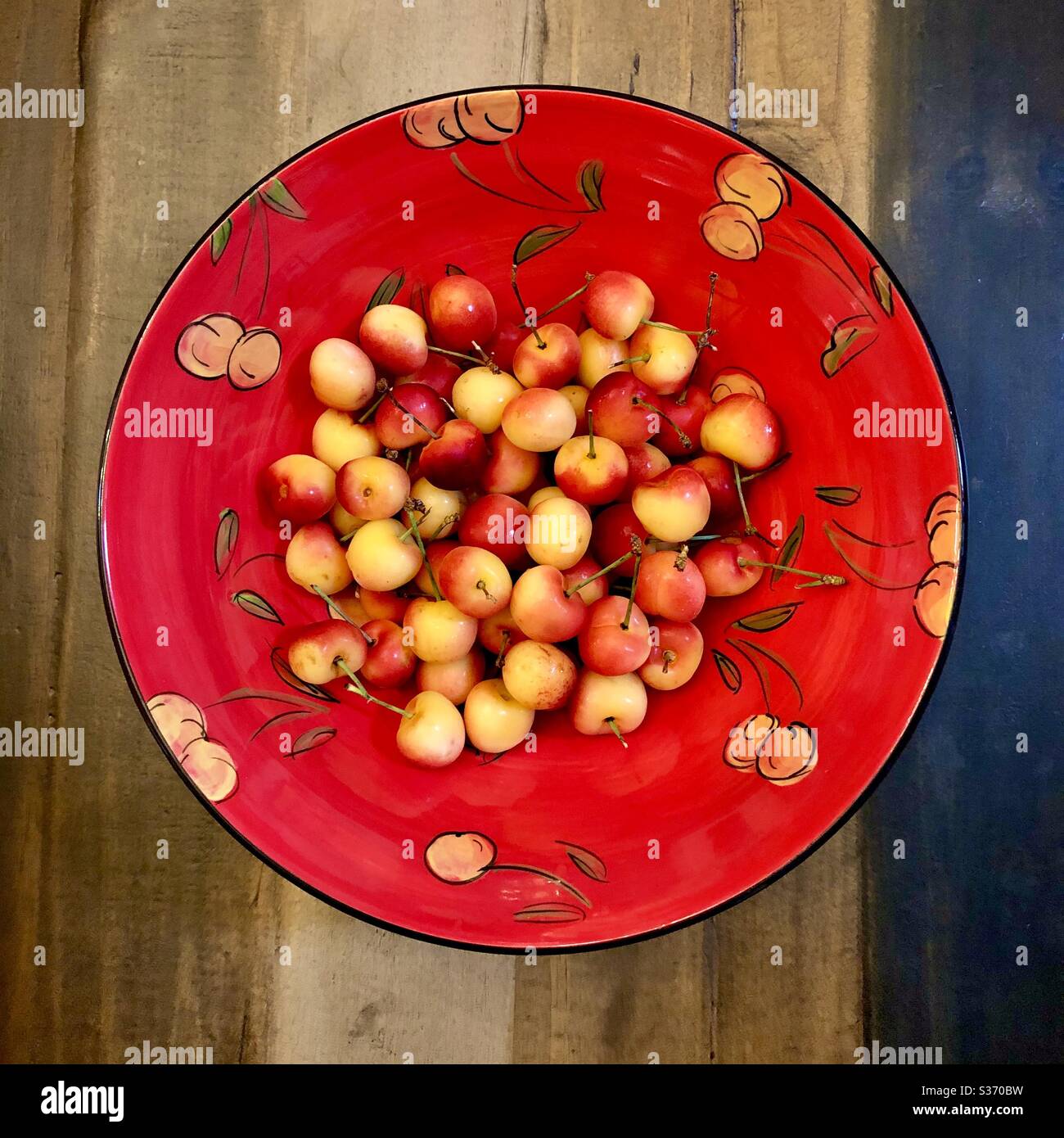 Panoramica di una ciotola di ciliegie Rainer in una ciotola in ceramica dipinta a mano con motivo di ciliegia Ranier. - Immagine stock catturata con smartphone