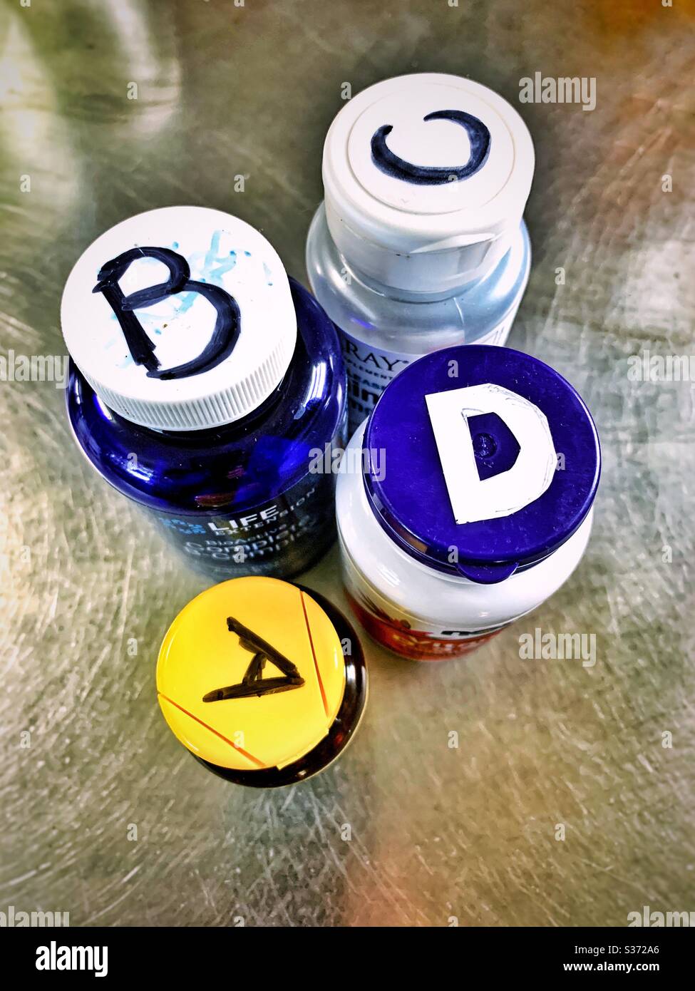 La lettera vitamine , A, B, C, D, bottiglie sul tavolo in cucina Foto Stock