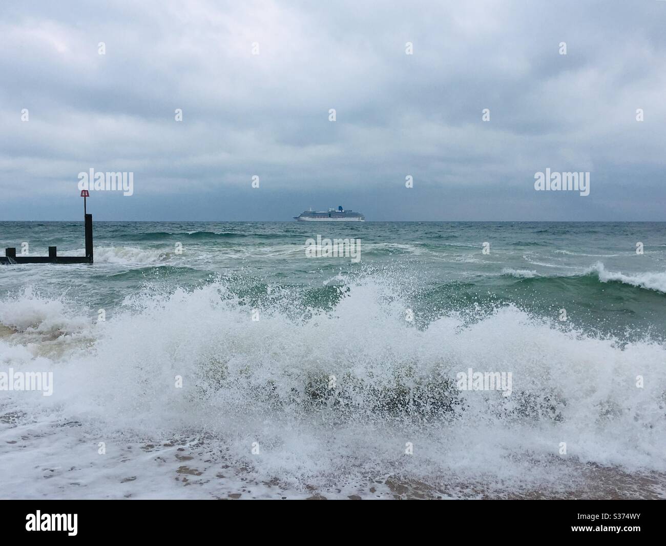 Onde crashing sulla spiaggia di Boscombe, con una nave da crociera P & o ancorata a Bournemouth Bay durante l'epidemia di Coronavirus 2020 giugno Foto Stock