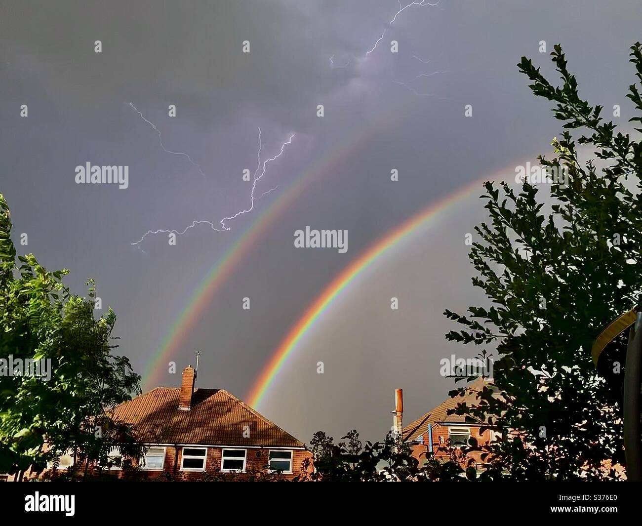 Raddoppia l'arcobaleno e il fulmine durante il temporale Foto Stock