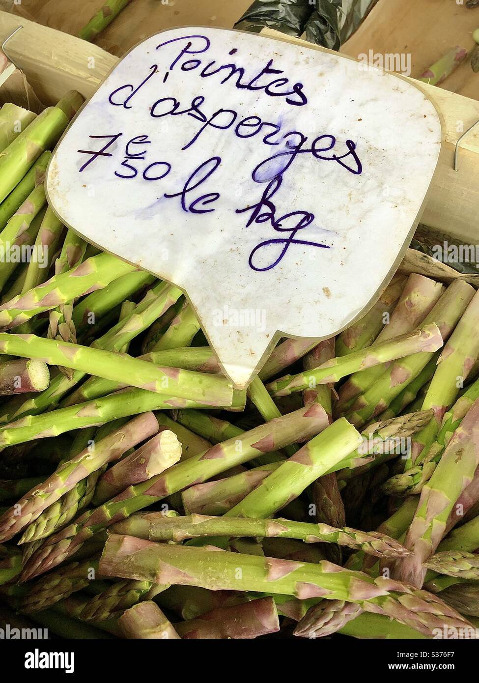 Giovani spighe fresche di asparagi verdi tinte viola sul mercato francese. Foto Stock