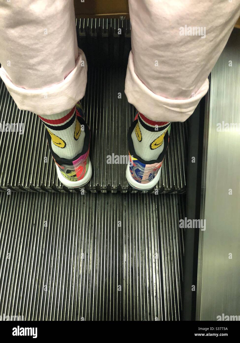 Ragazzo che indossa le salse rosa e felice smiley faccia calze sulla scala mobile della metropolitana di Londra UK - Immagine stock catturata con smartphone