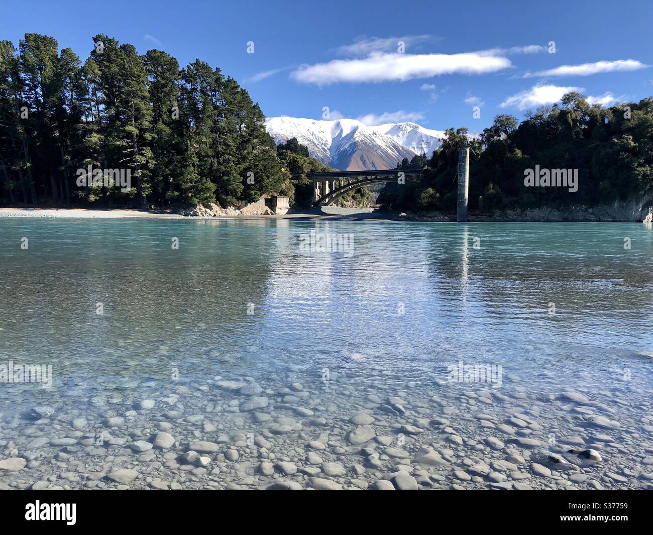 Fiume con ponte e sfondo di montagna Foto Stock