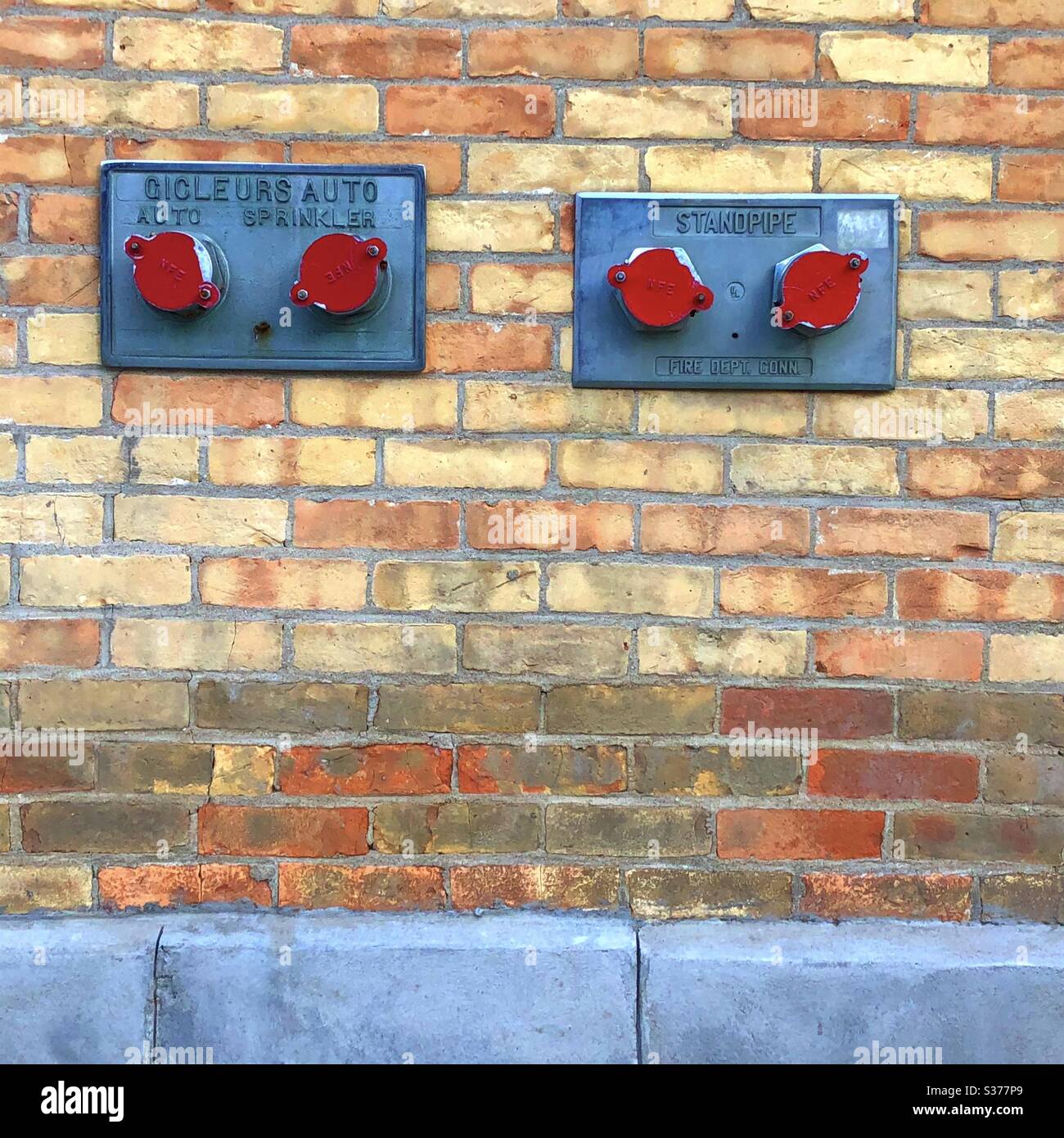 Connettori sprinkler coperti da tappi rossi sulla parete in mattoni gialli, Ottawa, Ontario, Canada, 2020 Foto Stock