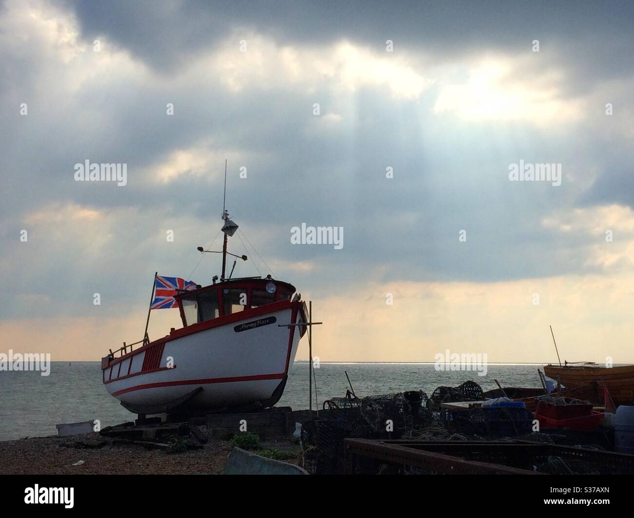 Una barca da pesca con una bandiera di Union Jack ormeggiata sulla spiaggia a un affare Kent UK Foto Stock