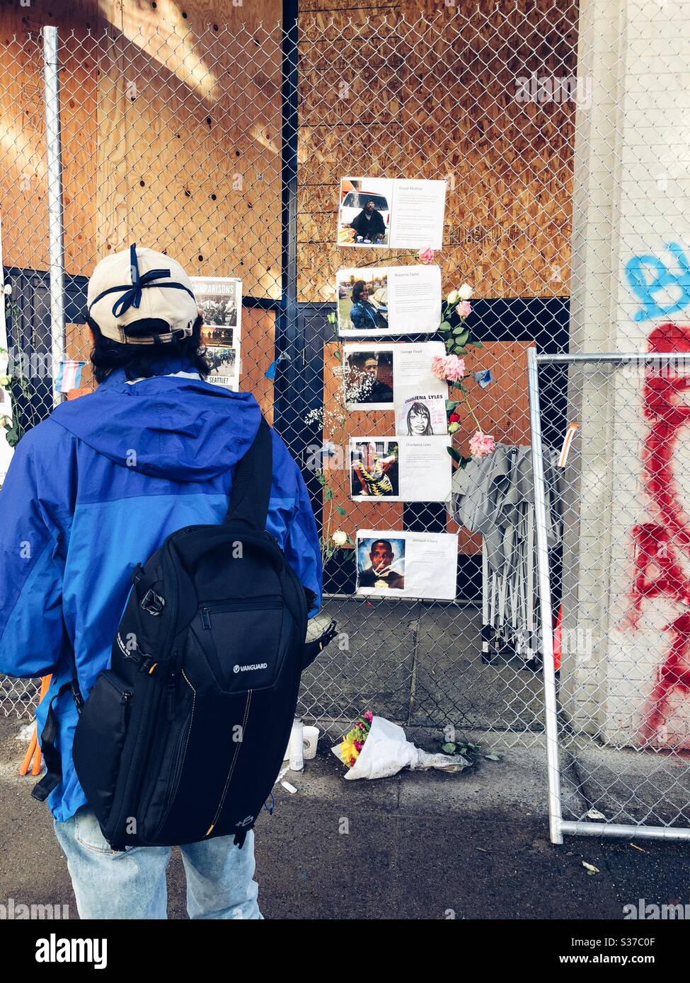 Fotografo indipendente che guarda il memoriale realizzato a fortuna per il popolo nero ucciso dalla polizia sulla recinzione che circonda il 12 ° distretto della polizia abbandonato a Capitol Hill a Seattle nel giugno 2020 Foto Stock