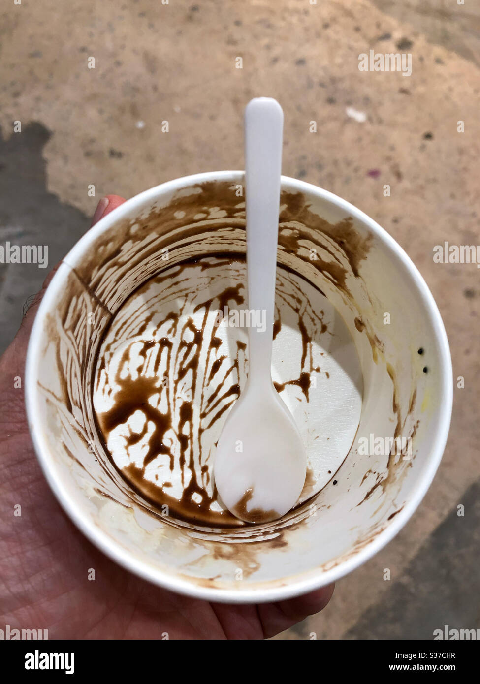 Una vasca vuota di gelato al cioccolato con un cucchiaio di plastica Foto Stock