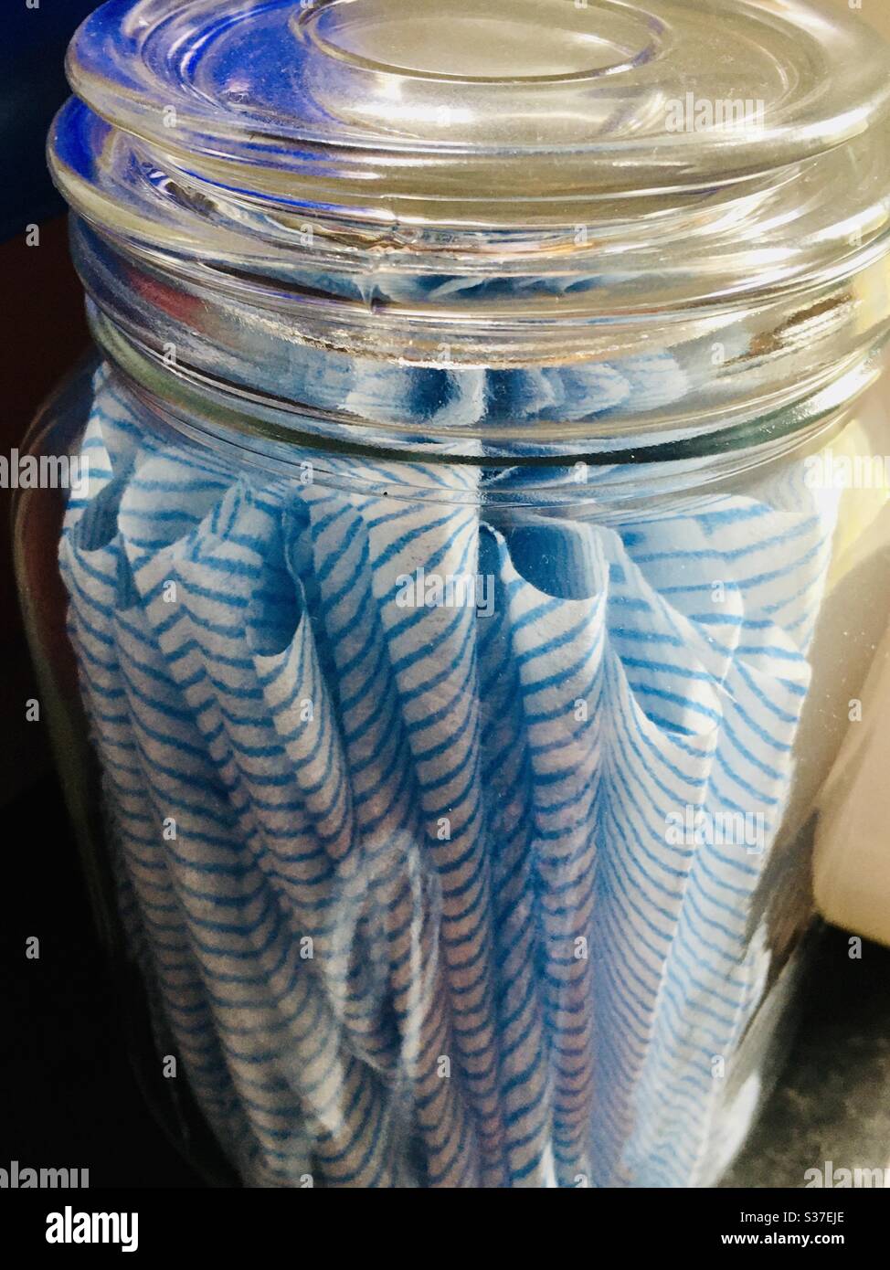 Vasetto di vetro di abiti bianchi e blu in una lavanderia Foto Stock