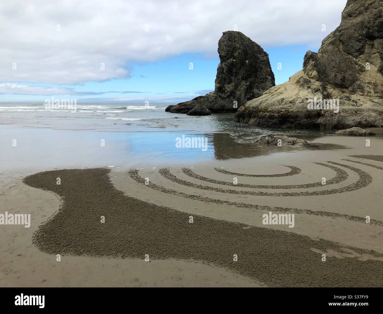 Marea crescente cancellando un labirinto di sabbia a Bandon, Oregon, Stati Uniti. Foto Stock