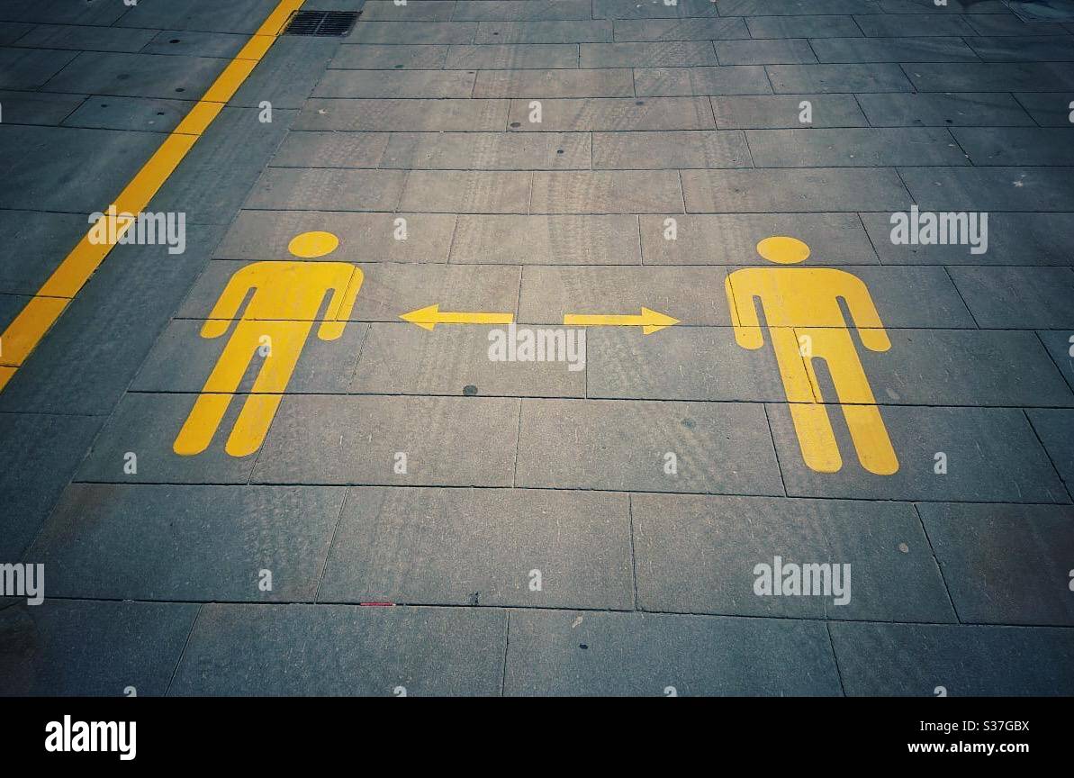 Marcatori di distanza sociale sulla strada. Figure dipinte di giallo sul pavimento. 2 metri di distanza. Foto Stock
