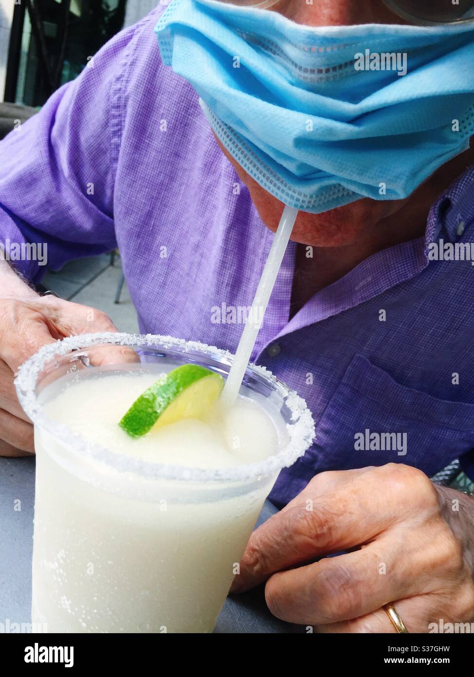 Scena umorosa di un uomo che beve una margarita attraverso una paglia che indossa una maschera protettiva. Questo è durante la riapertura di ristoranti di New York City dal pandemico coronavirus, 2020 giugno, New York, Stati Uniti Foto Stock