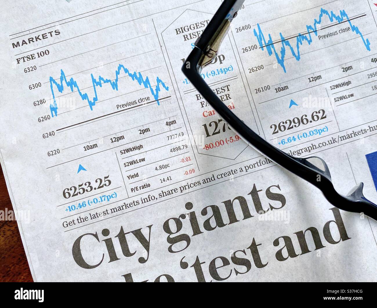 Concetto di business e finanza. Primo piano di un giornale finanziario con grafico che mostra i mercati di FTSE 100 in costante declino durante la crisi del coronavirus. Mercato crashing. Con occhiali da lettura - Immagine stock catturata con smartphone