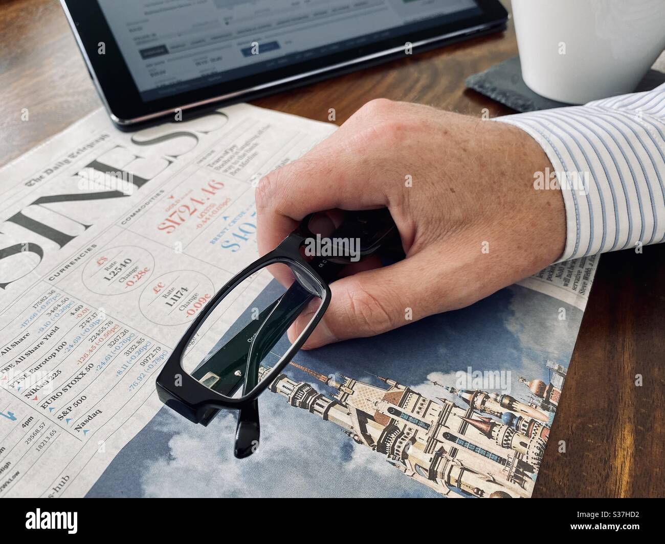 Concetto di business e finanza. Primo piano visualizza il mercato trader recuperare notizie finanziarie con caffè del mattino, tablet e quotidiano aziendale. I mercati di FTSE 100 sono in declino durante la crisi del coronavirus Foto Stock