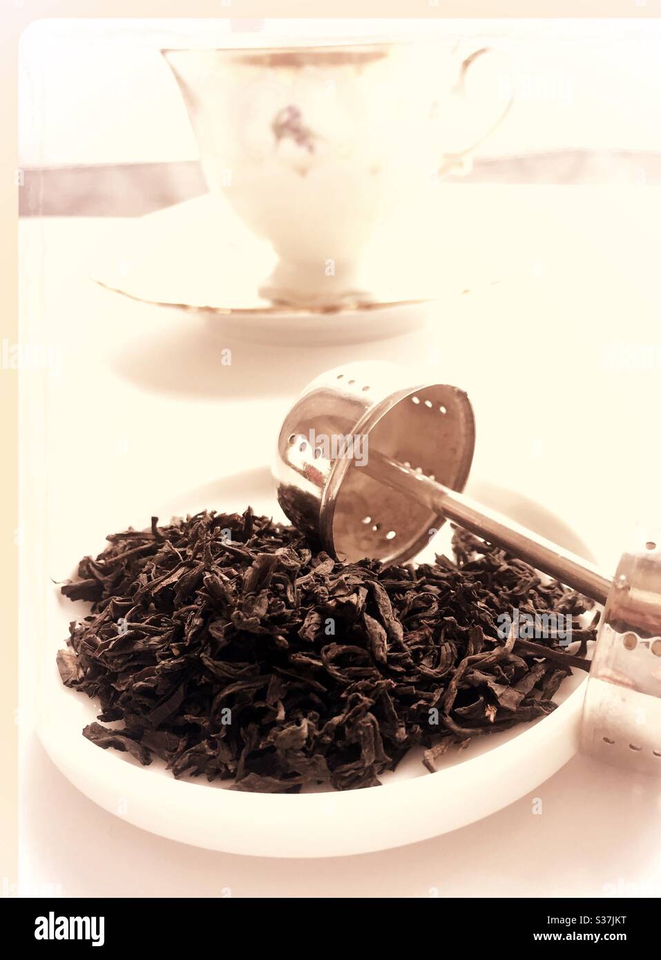 Tè sciolto e un infusore di argento sterling di fronte a trovare la tazza di tè Cina e piattino Foto Stock