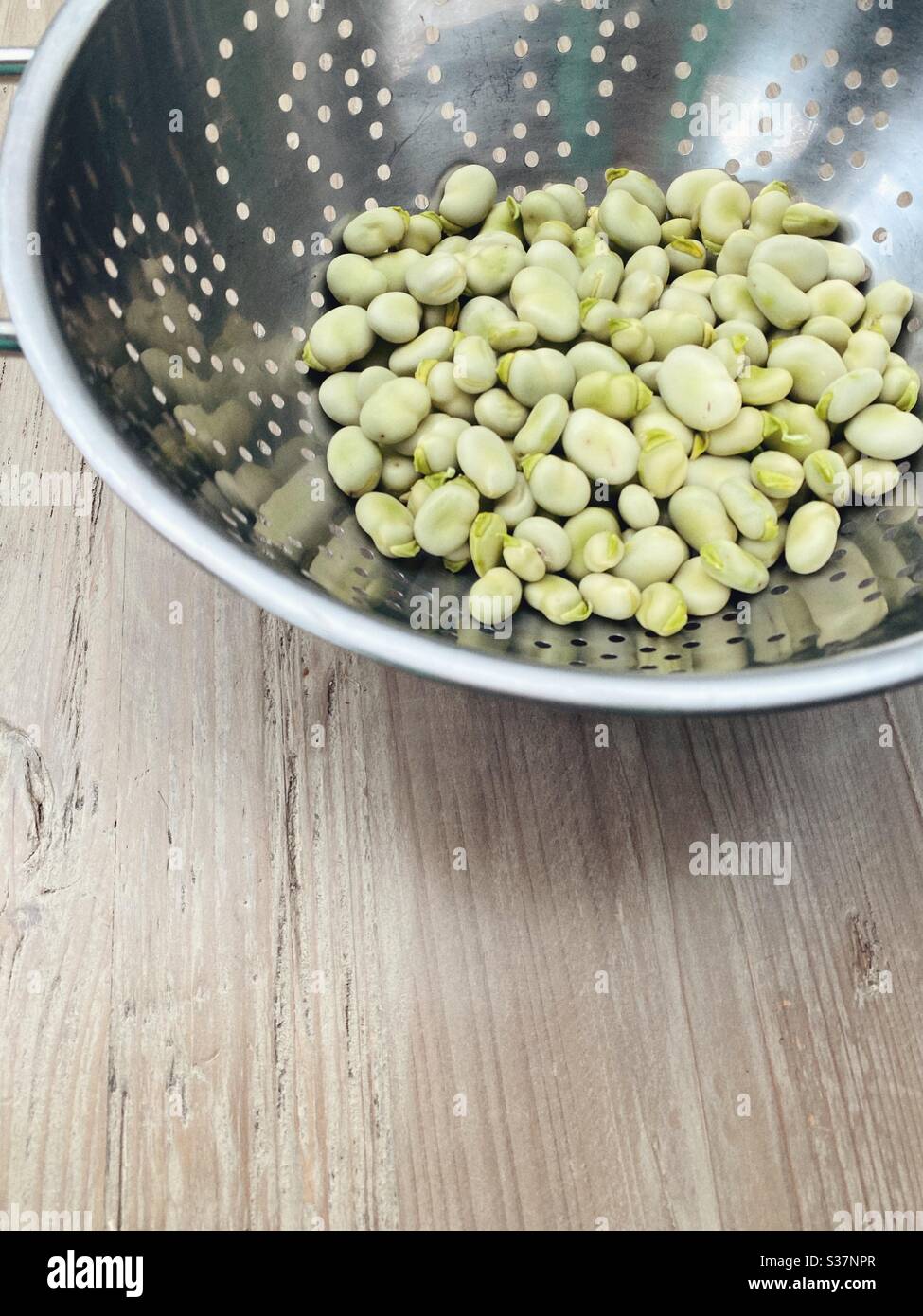 Fagioli appena podded in un colander metallico su un tavolo di legno, spazio vuoto, - Immagine stock catturata con smartphone