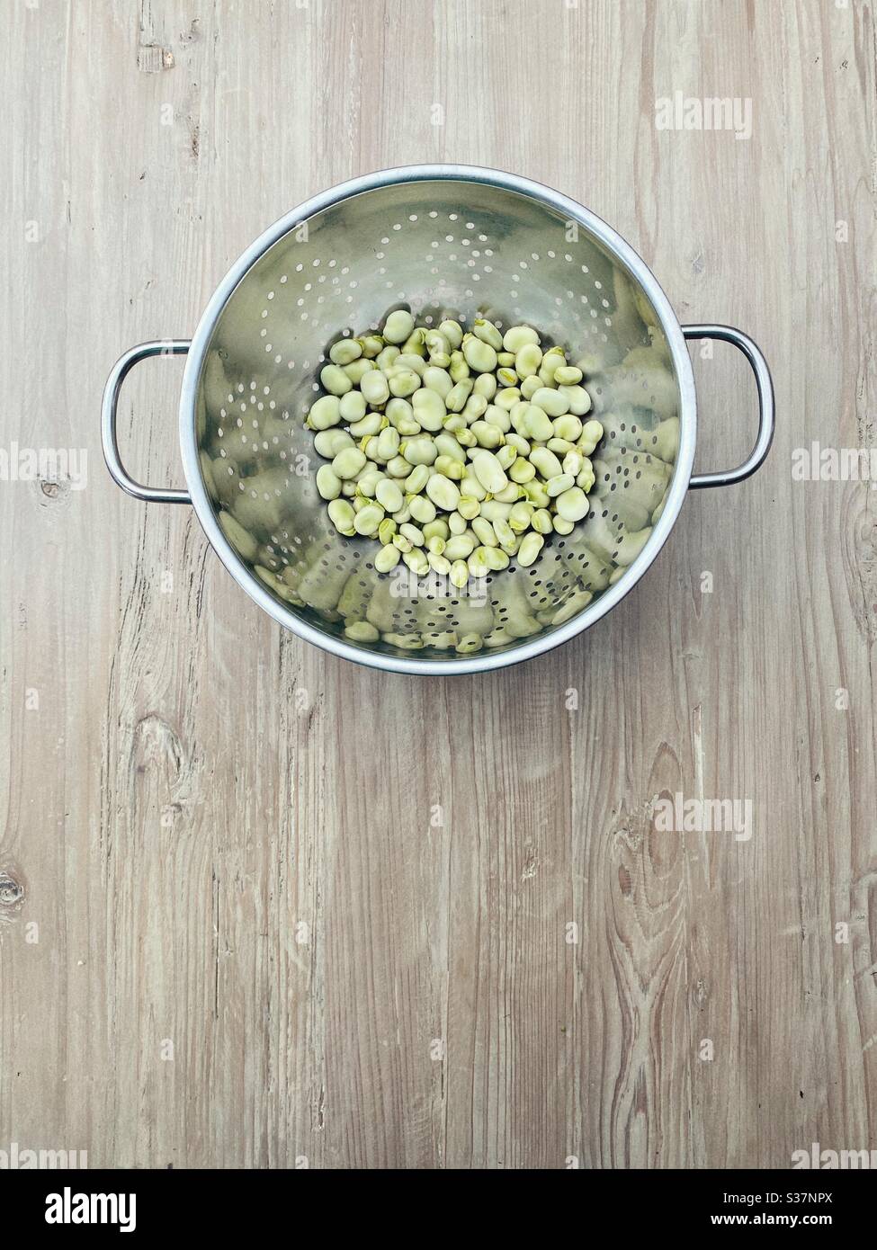 Flatlay fagioli di fave appena fatti in pezzetti in un colander di metallo, rustico, minimalista, dall'alto con spazio vuoto nella cornice - Immagine stock catturata con smartphone