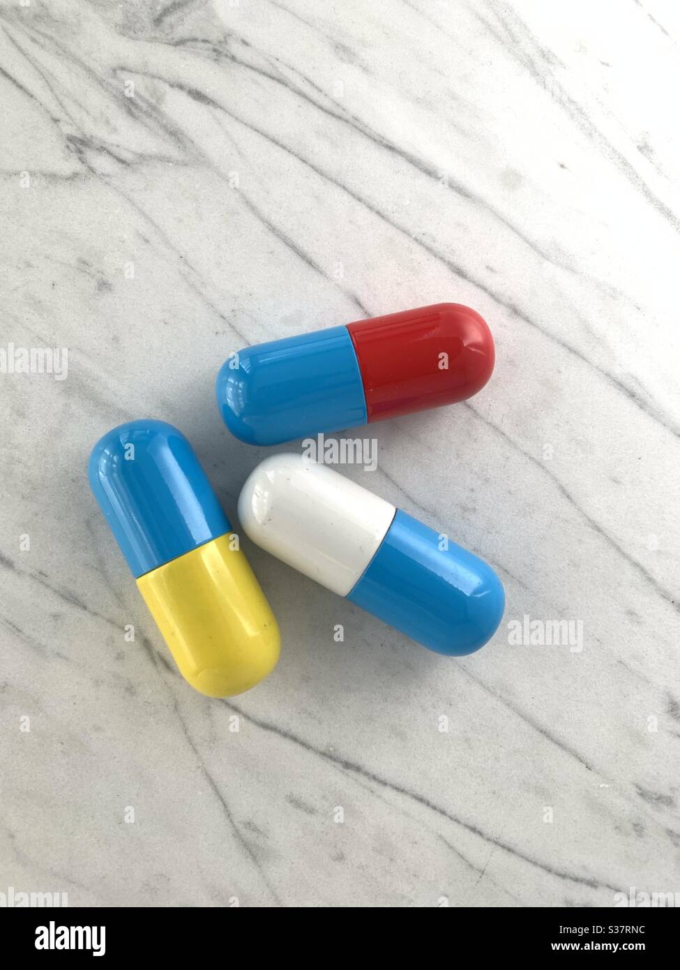 3 pillole su un banco di marmo, pillole di sostegno non un prodotto, solo a forma di capsula - Immagine stock catturata con smartphone
