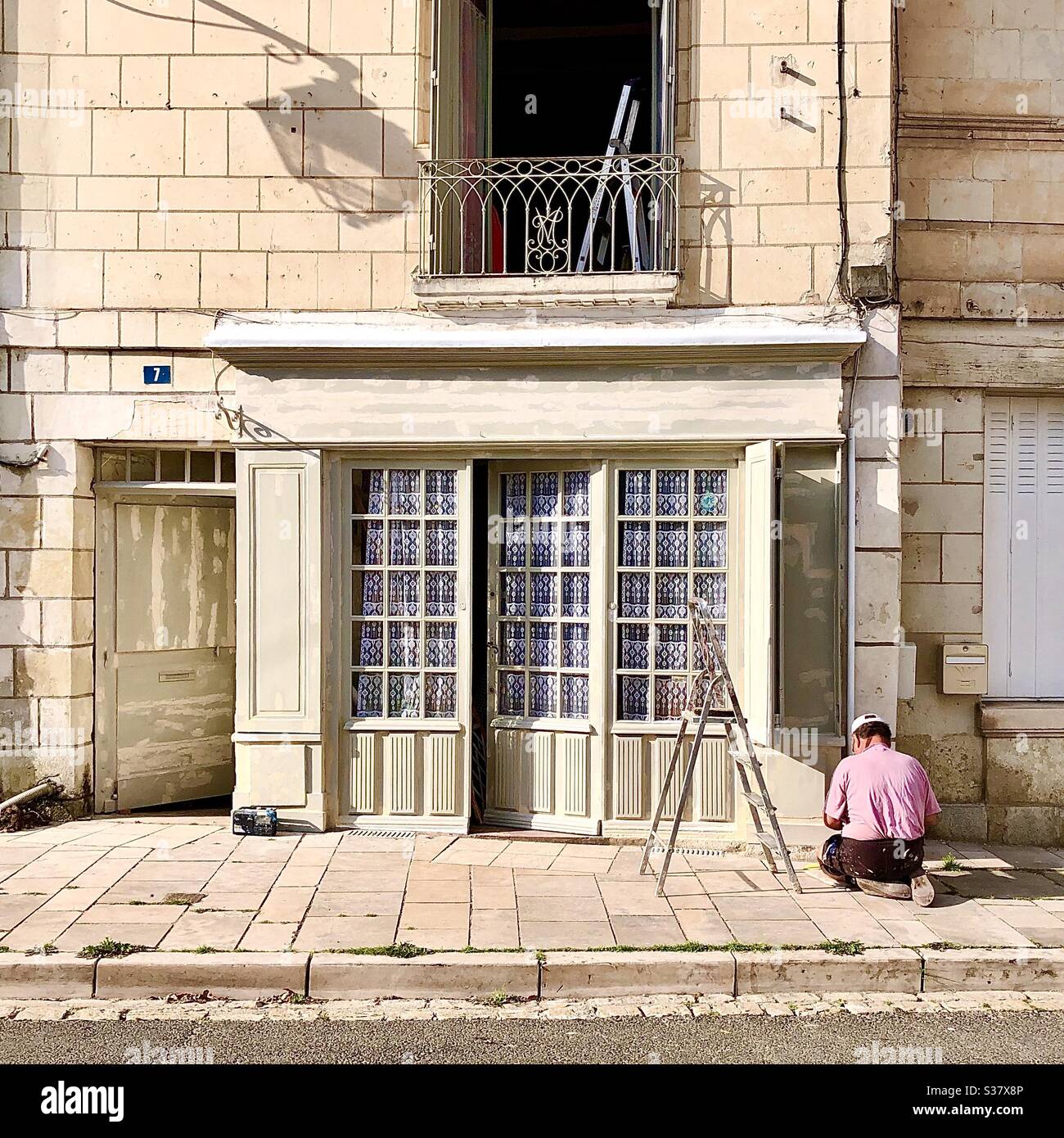 Uomo pittura esterno della vecchia casa di città francese, sud-Touraine, Francia. Foto Stock