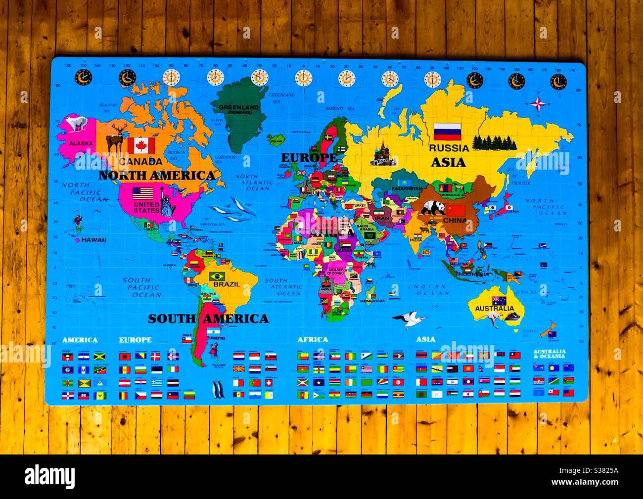 Un puzzle mappa del mondo molto grande, con bandiere, animali, e paesi a colori, allestito su un pavimento di legno di pino. 3D. Molto informativo. Simboli geografici, punti di riferimento, icone e altro ancora. Grandi pezzi. Giochi per bambini Foto Stock