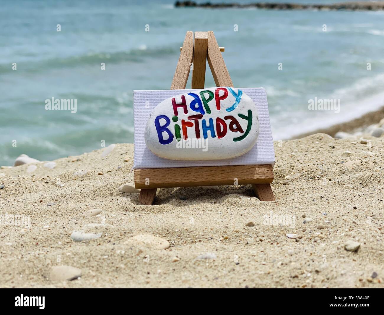 Buon compleanno, messaggio creativo con un testo multicolore scolpito su una pietra - Immagine stock catturata con smartphone