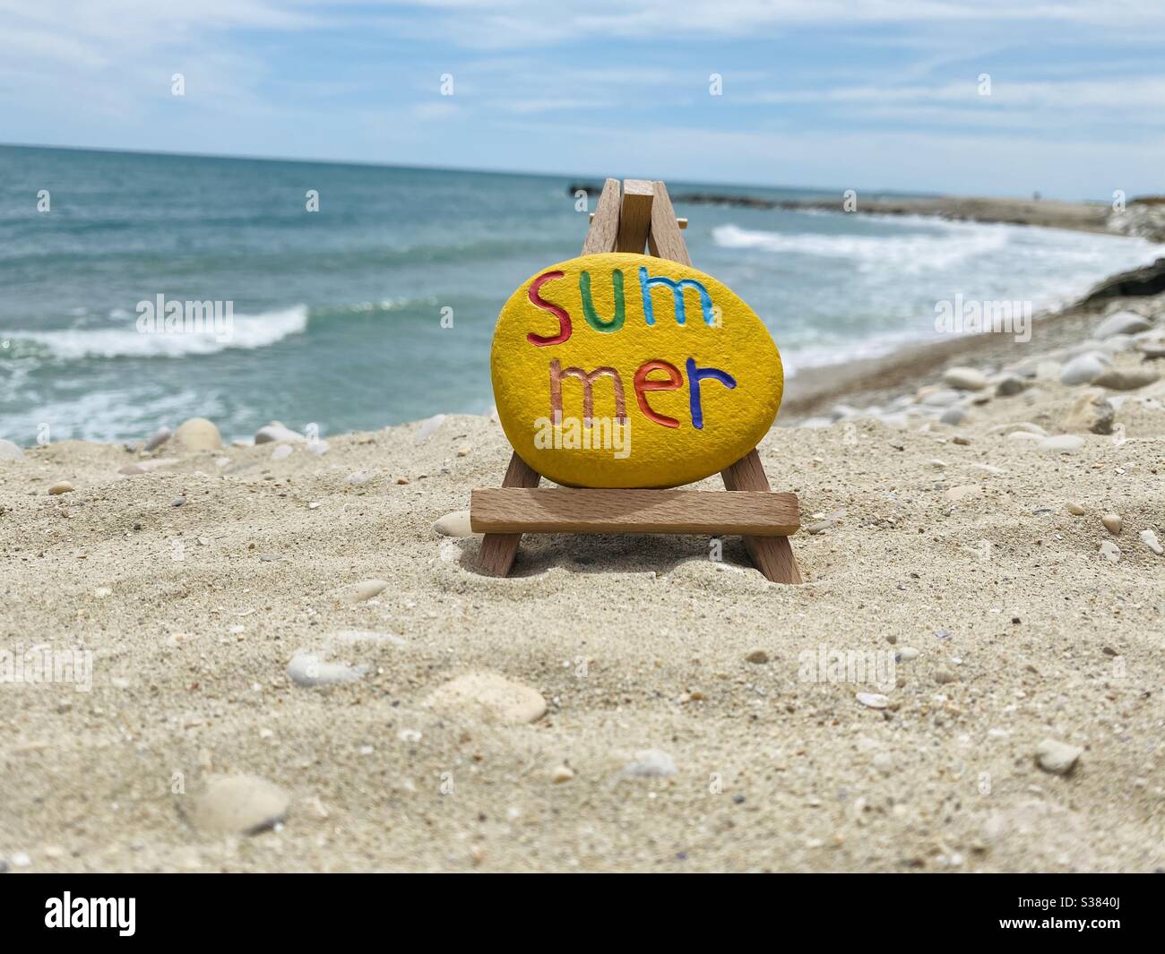 Parola estiva con testo multicolore su una pietra sulla spiaggia - Immagine stock catturata con smartphone
