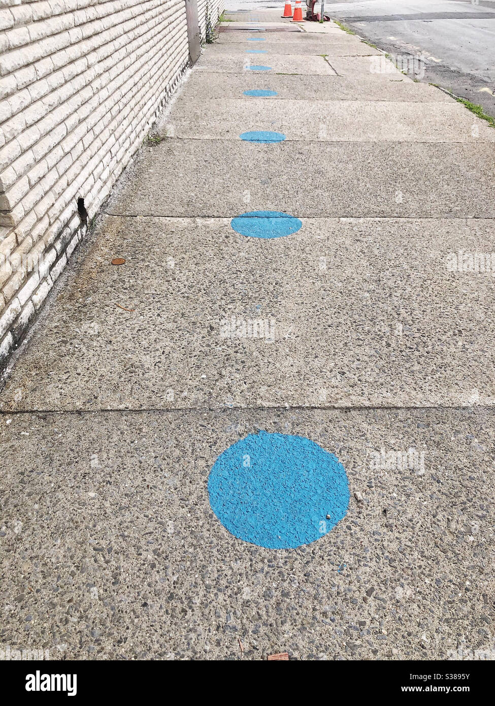 Cerchi blu sul marciapiede per le persone in linea per lo spazio se stessi per la distanza sociale Foto Stock