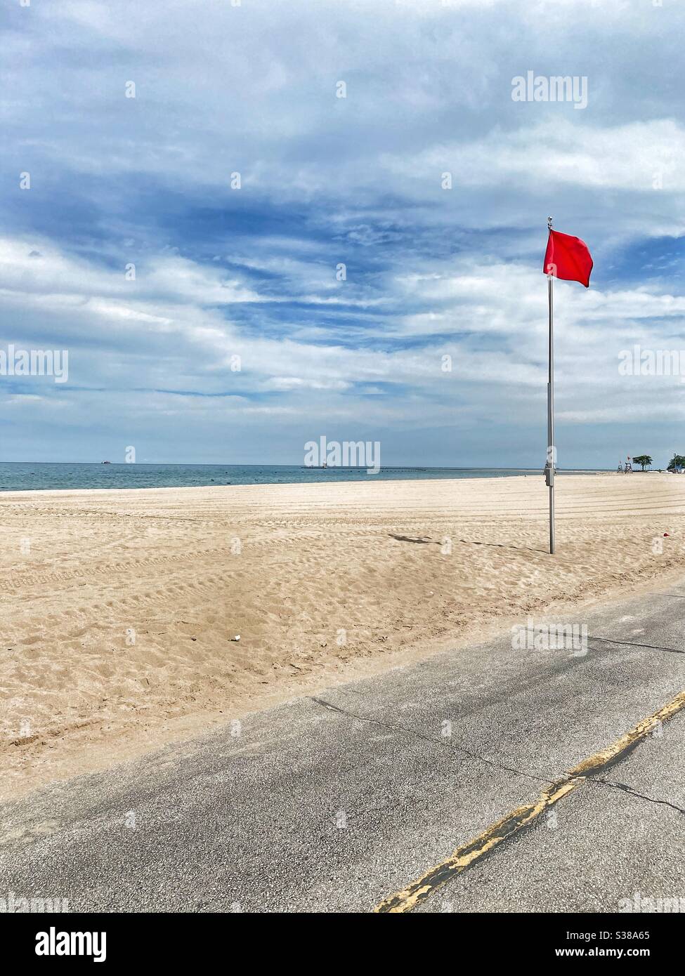 Spiaggia vuota con bandiera rossa che proibisce il nuoto. La spiaggia è chiusa e non è consentito a nessuno. Foto Stock