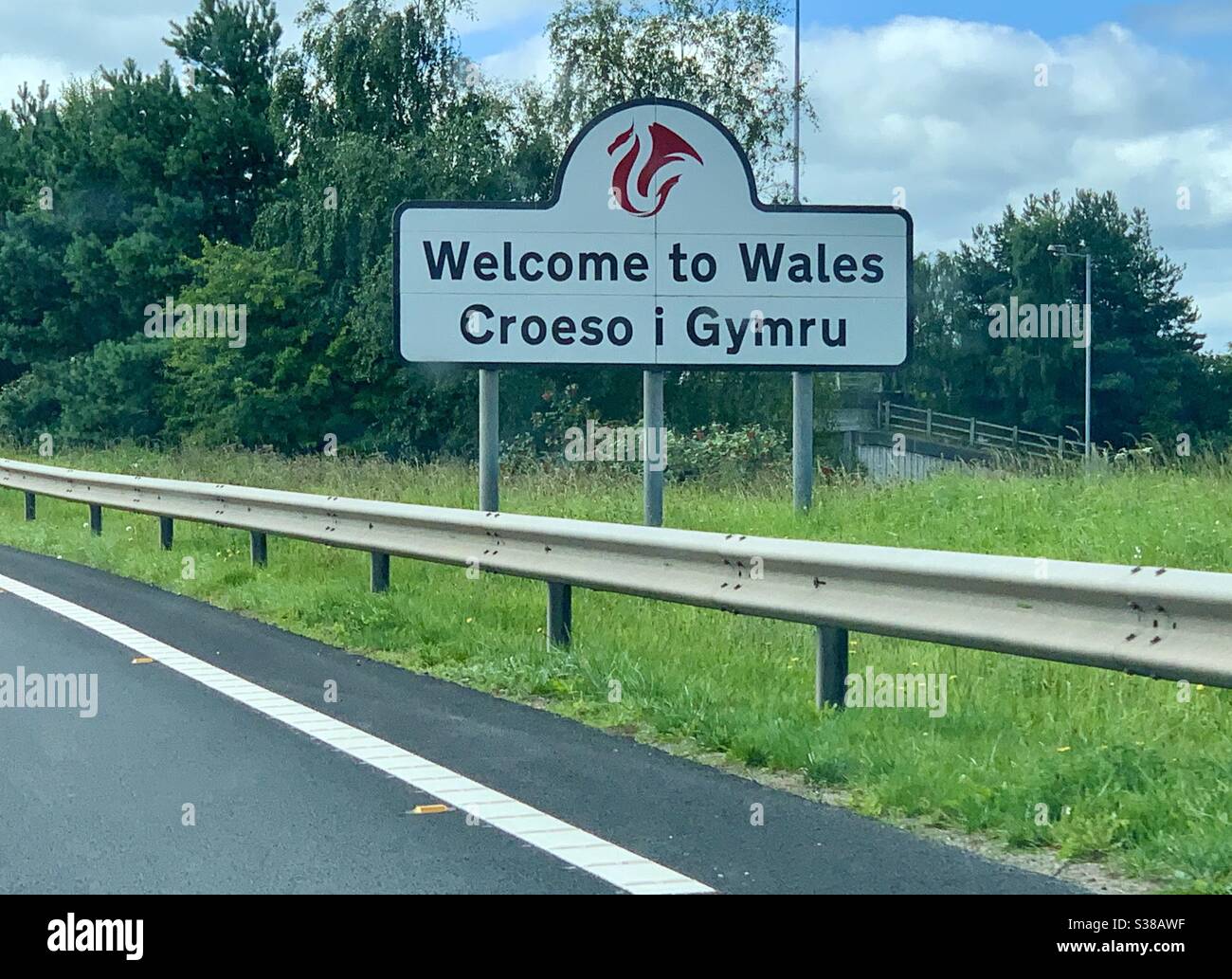 Il cartello Welcome to Wales sul confine gallese-inglese, visto attraverso il parabrezza dell'auto. Foto Stock