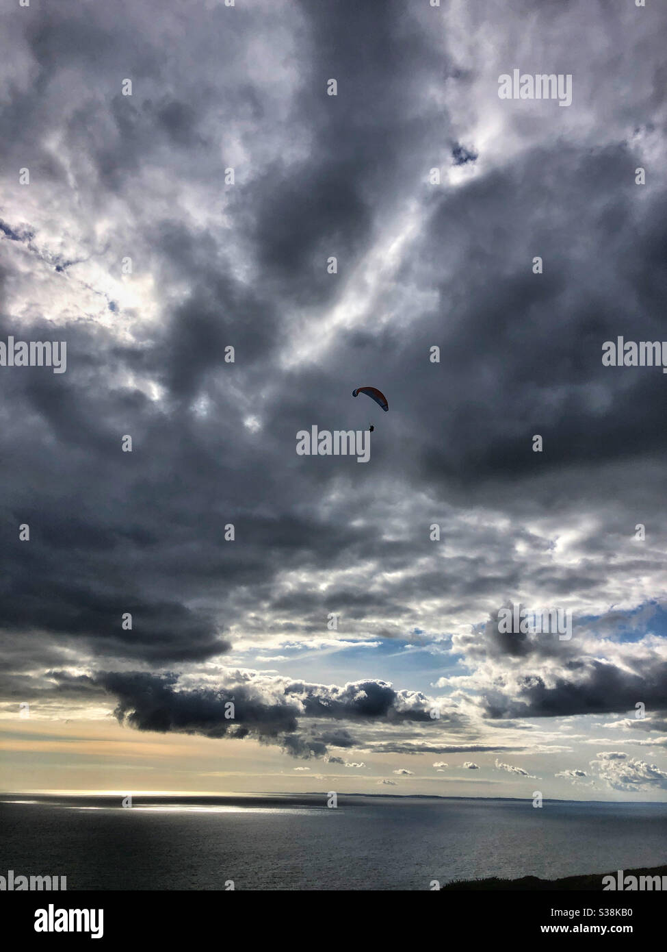 Lone parapendio contro un cielo rosticante, Rhossili, Gower, Galles. Foto Stock