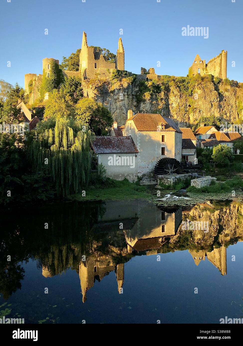 Luce serale sulle rovine château e riflessioni nel fiume di Angles-sur-l'Anglin nella Vienne, Francia. - Immagine stock catturata con smartphone