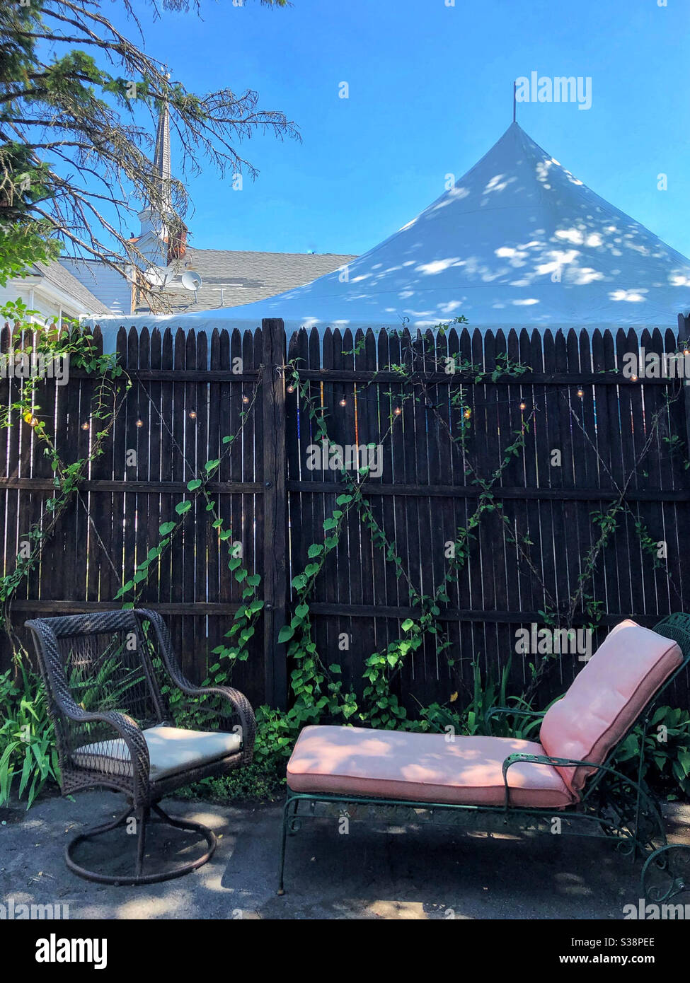 Cortile con recinzione e salotto ombreggiato, tenda nel cortile accanto - Immagine stock catturata con smartphone