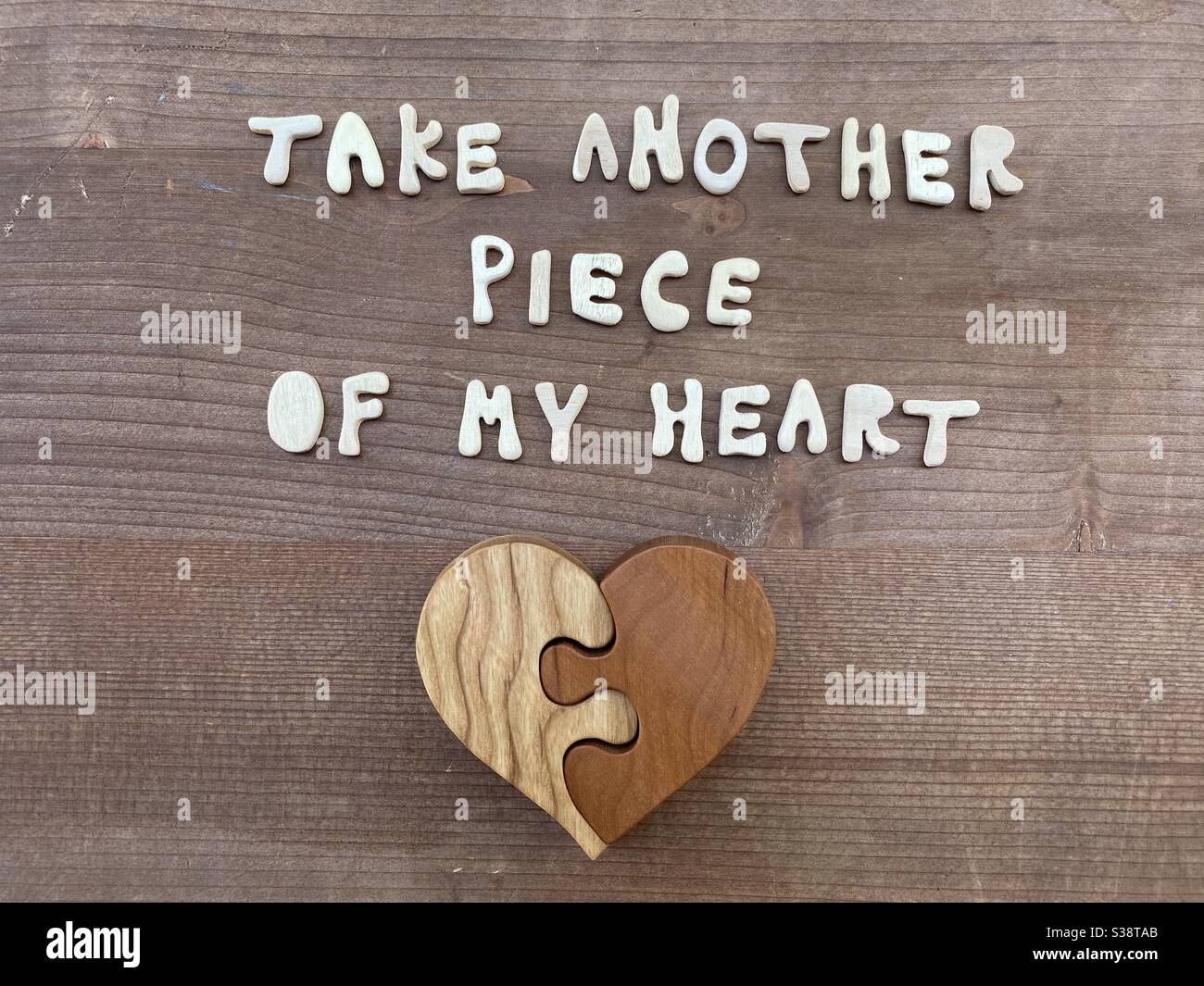 Prendete un altro pezzo del mio cuore, messaggio d'amore composto da lettere in legno fatte a mano e un puzzle cuore in legno Foto Stock