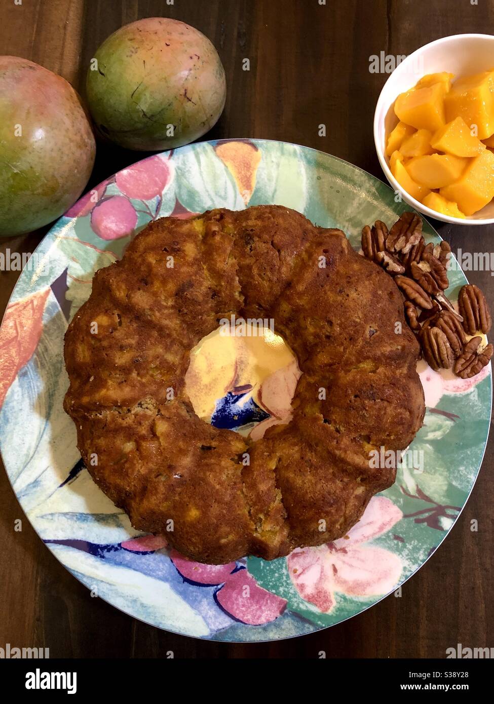 Torta di mango in una padella Bundt con noci pecan e pezzi di mango sul lato. - Immagine stock catturata con smartphone