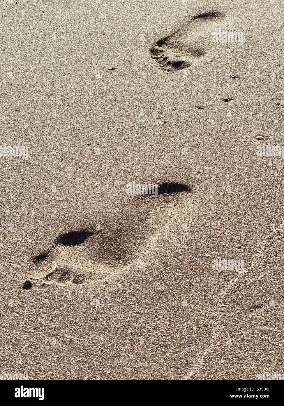Due impronte umane nella sabbia alla luce del mattino Foto Stock