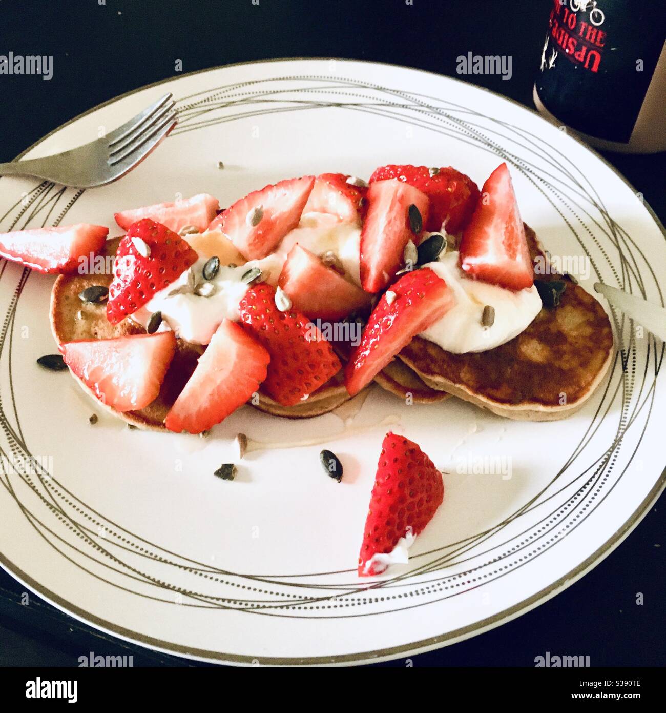 Pancake conditi con yogurt greco, fragole e semi Foto Stock