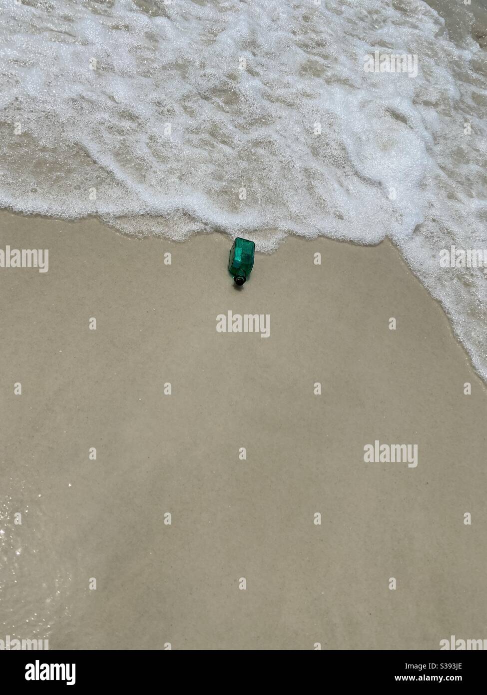 Guardando verso il basso su una bottiglia di vetro verde lavata a terra la spiaggia Foto Stock