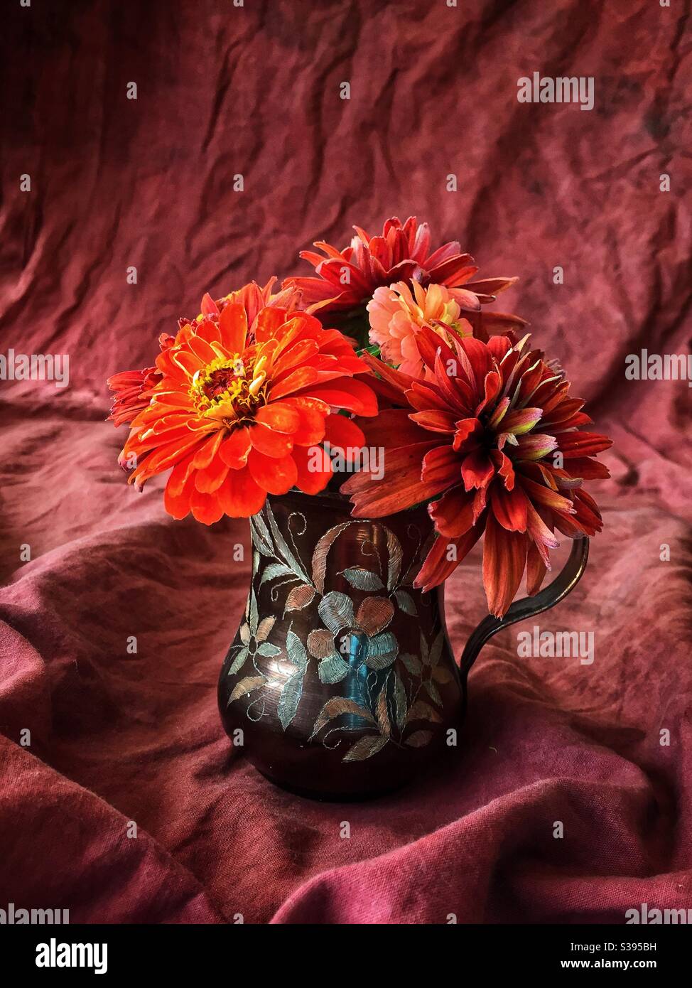 Piccolo bouquet di zinnie colorate in autunno e rudbeckia in una caraffa di bronzo. - Immagine stock catturata con smartphone
