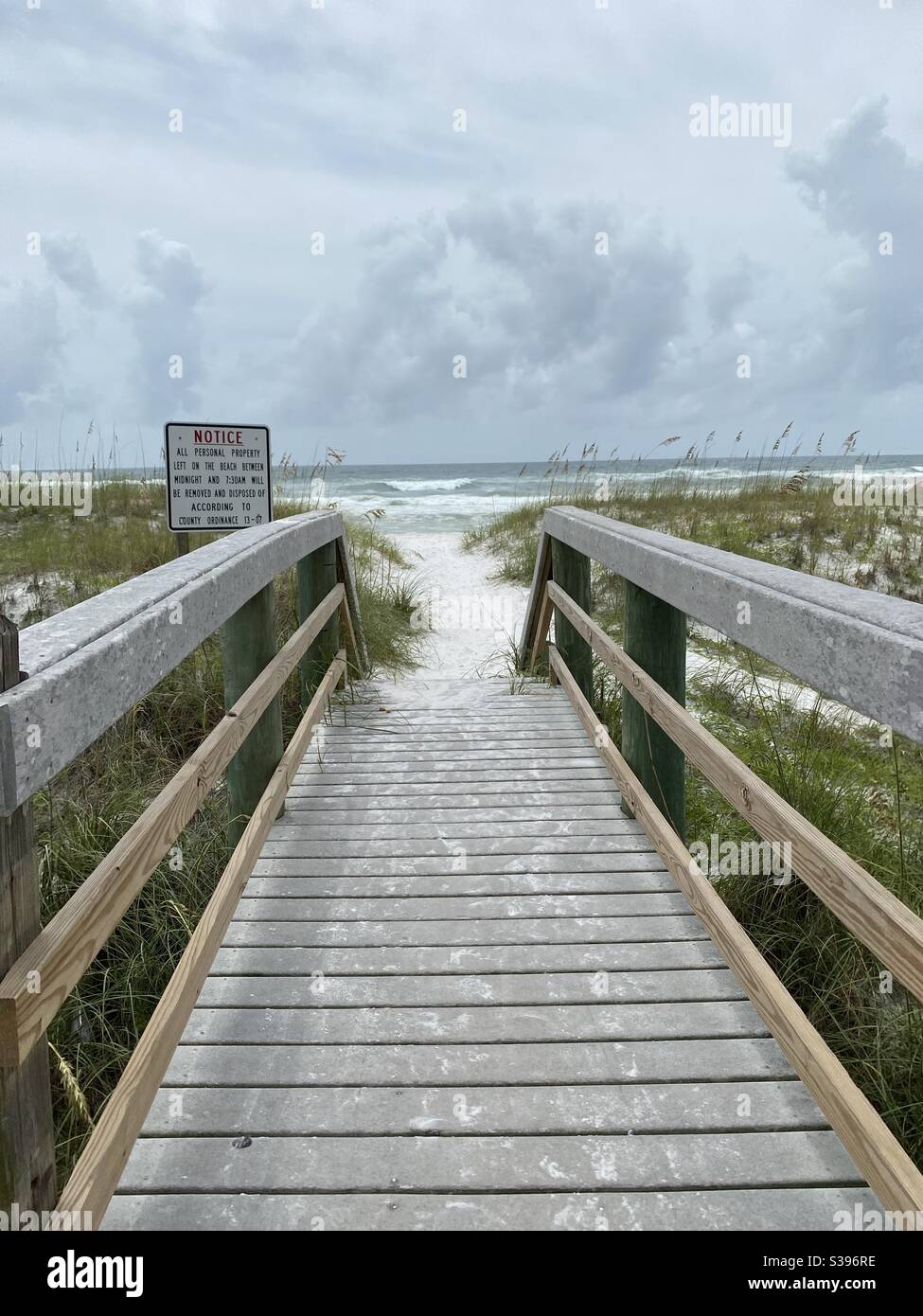 Passerella per la spiaggia con cieli tempestosi e Golfo turbolento Di acqua del Messico dagli effetti dell'uragano Laura 2020 agosto Florida Foto Stock