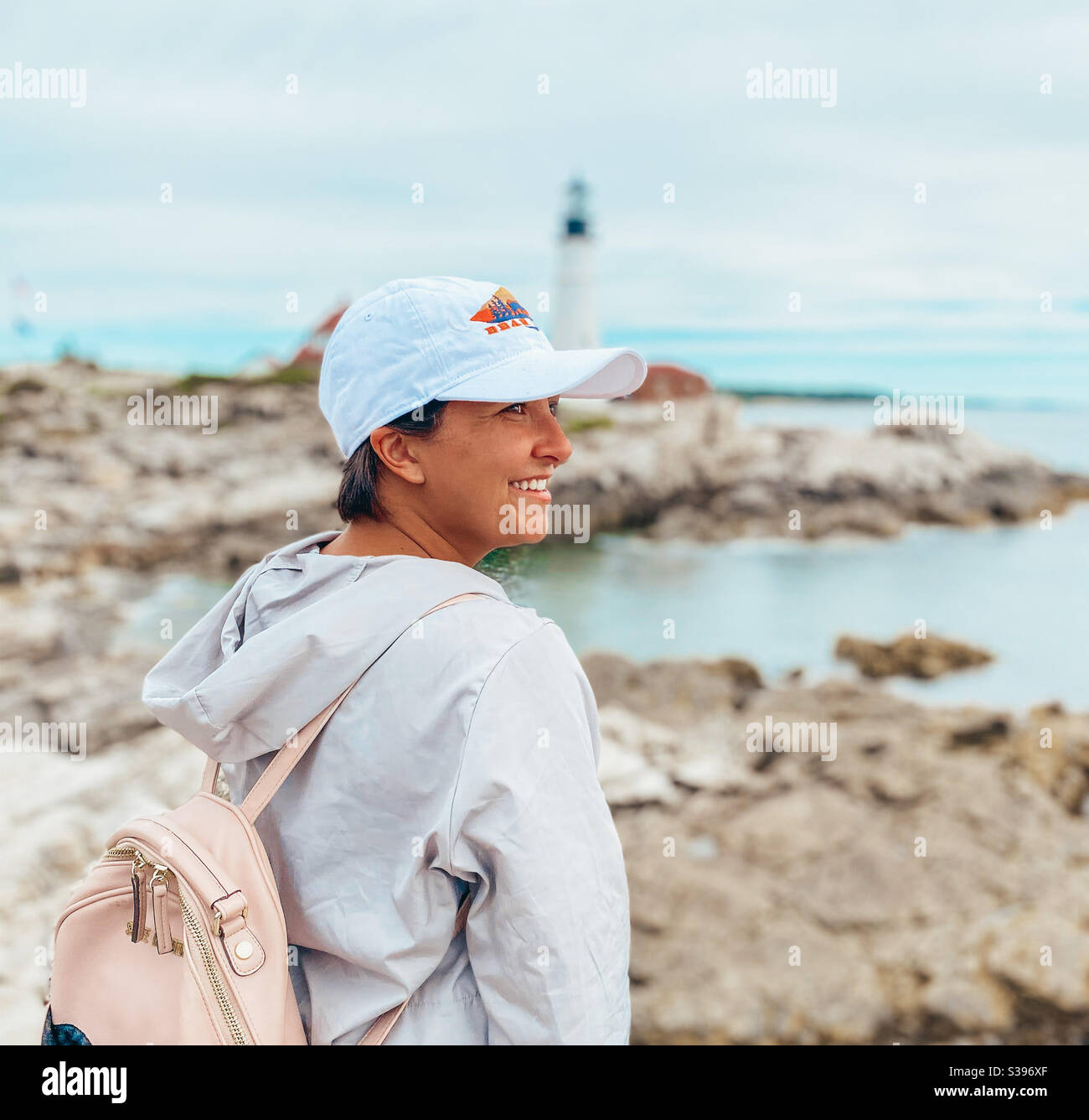 Ragazza che esplora la costa con faro e costa rocciosa dentro sfondo Foto Stock