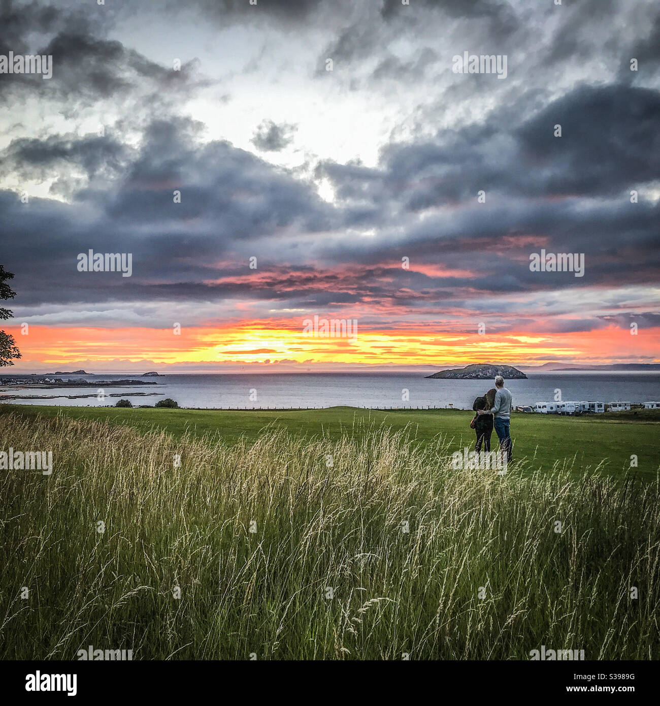 Abbracciando la coppia guardando il tramonto a North Berwick in Scozia Foto Stock