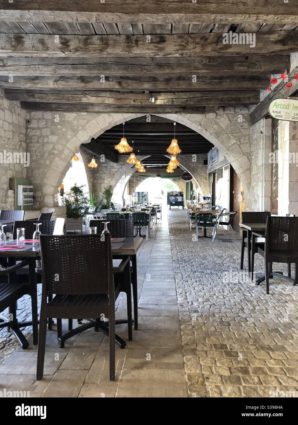 Tavoli da ristorante allestiti sotto la galleria in città Di Eymet in Francia Foto Stock