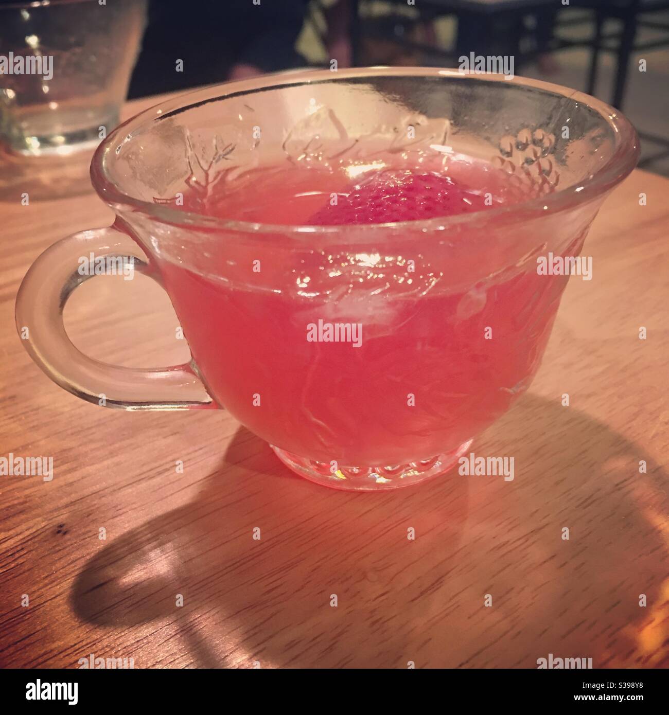 Bella tazza di punch trasparente con un grazioso punzone di frutta rosa con una fragola Foto Stock