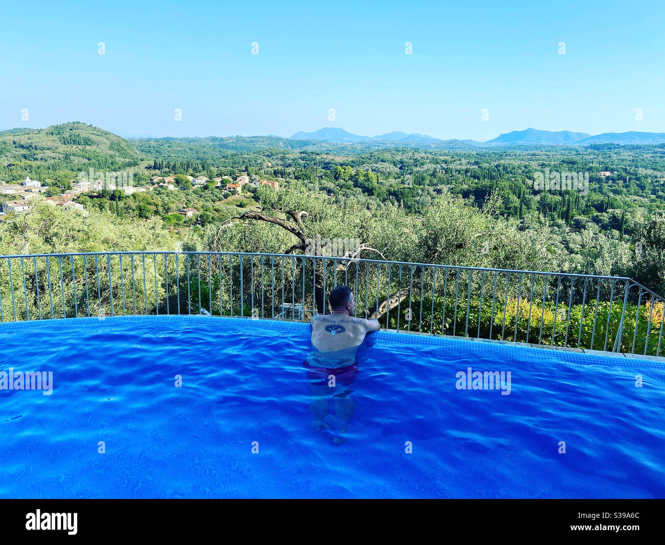 Uomo in piscina con vista sul verde paesaggio - Immagine stock catturata con smartphone
